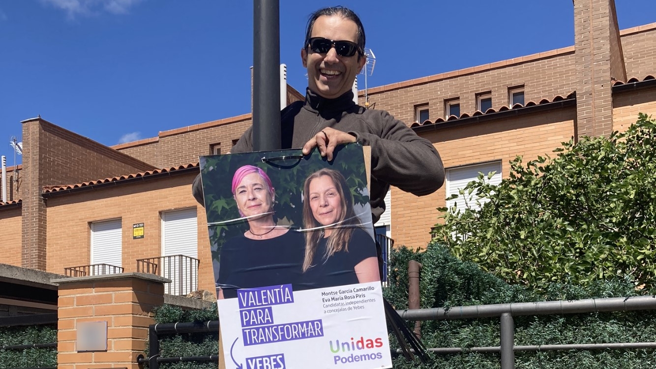 Un miembro de la candidatura, colocando uno de los carteles electorales//Imagen: Unidas Podemos.